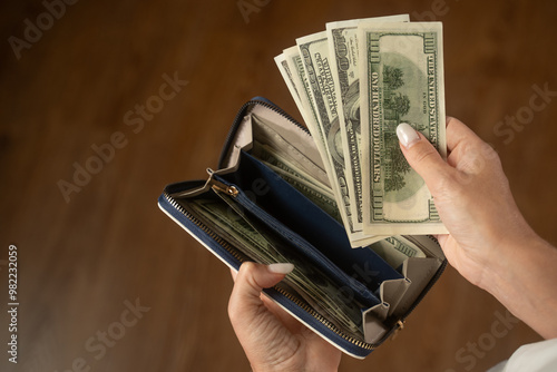 Woman counts us dollar bills while taking them out of a blue wallet. The scene highlights the act of managing cash and emphasizes personal finance and budgeting photo