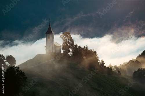 Jamnik, Slovenia - Magical foggy golden summer sunrise at Jamnik St.Primoz church. photo