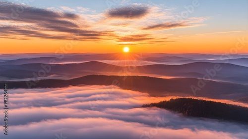 Stunning sunrise over mountains, casting warm light across valleys shrouded in mist. A tranquil moment in nature's beauty.