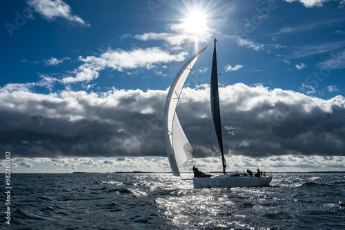 Segelyacht mit Gennaker vor atemberaubenden Wolken mit Sonne 