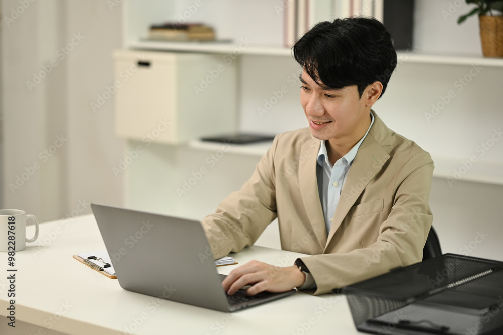 Handsome young businessman in formal suit working with laptop at office Handsome young businessman in formal suit working with laptop at office