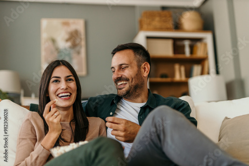 An adult couple watch movie, series on television and eat popcorn at home photo