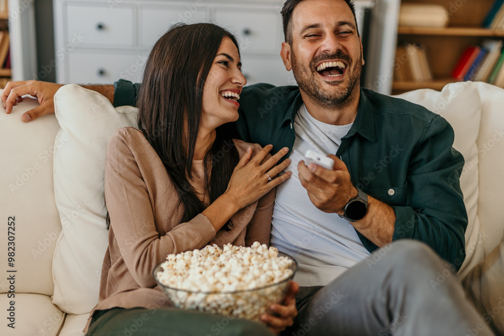 Shot of a beautiful happy couple sitting on the sofa in the living room at home, laughing and watching TV. Shot of a beautiful happy couple sitting on the sofa in the living room at home, laughing and watching TV.