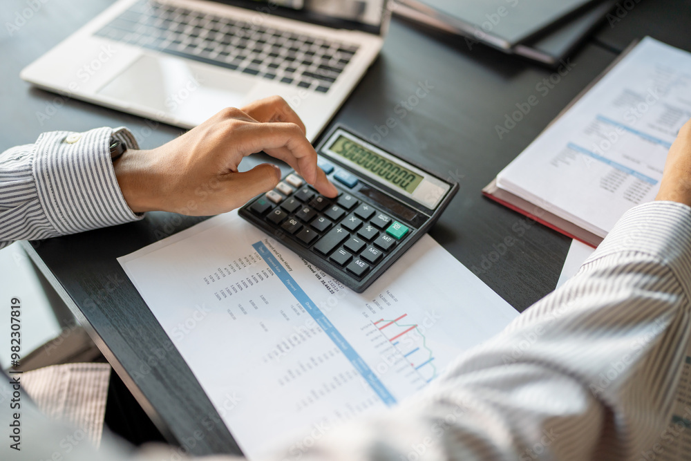 Businessman Accountant analyzing investment charts Invoice and pressing calculator buttons over documents. Accounting Bookkeeper Clerk Bank Advisor And Auditor Businessman Accountant analyzing investment charts Invoice and pressing calculator buttons over documents. Accounting Bookkeeper Clerk Bank Advisor And Auditor