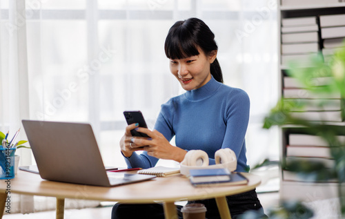 Smile asian woman working from home on laptop, freelance work online with phone and laptop documents 