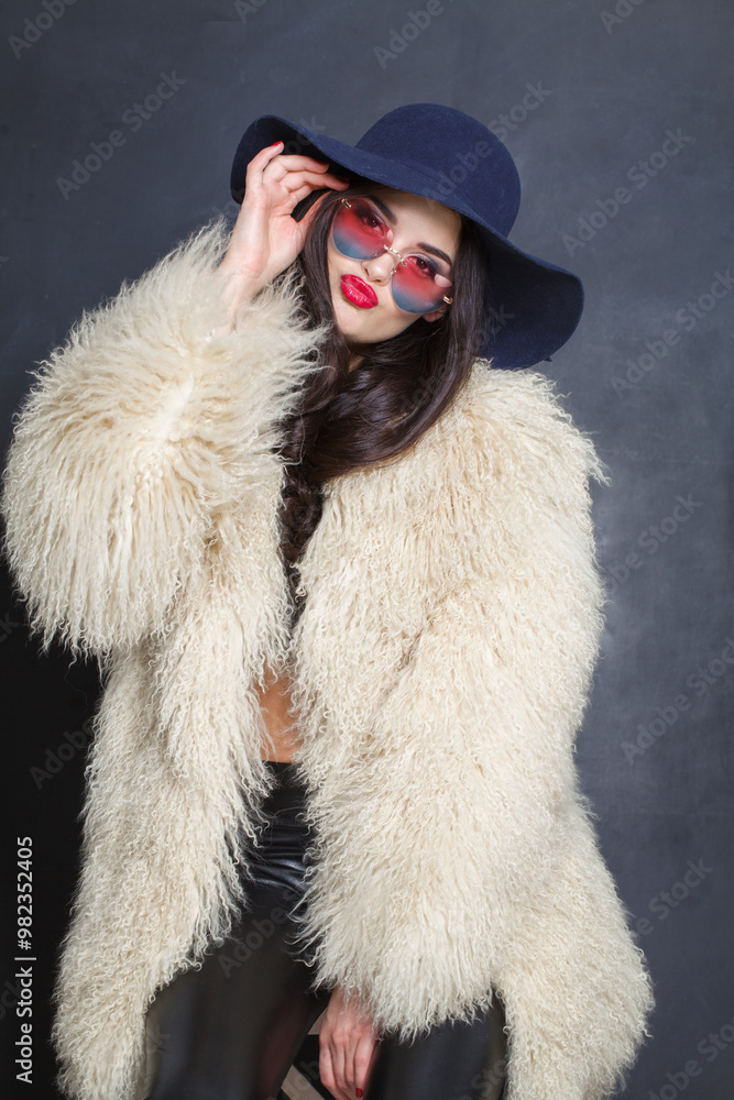 Pretty fashion model woman in blue classic hat and white fur coat posing indoor, elegance fashion beauty portrait Pretty fashion model woman in blue classic hat and white fur coat posing indoor, elegance fashion beauty portrait