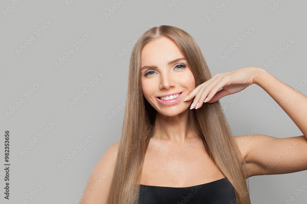 Obraz premium Close-up woman face. Model with long brown hair and make-up on grey background. Beauty, hair care and cosmetic portrait