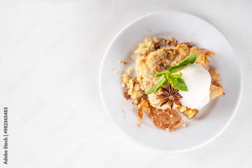 Apple Crumble Dessert, crisp cobbler with Ice Cream, crumble pie with crunchy dough topping in baking dish and plate, with ice cream scoop on white kitchen table Apple Crumble Dessert, crisp cobbler with Ice Cream, crumble pie with crunchy dough topping in baking dish and plate, with ice cream scoop on white kitchen table