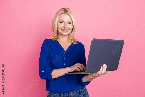 Photo portrait of attractive retired woman hold netbook dressed stylish blue clothes isolated on pink color background