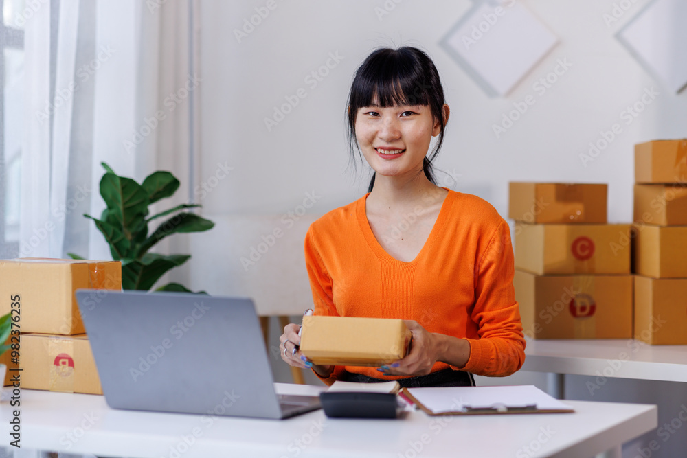 Asian female SME ecommerce business owner prepares package box for customer and delivery check balance. Asian female SME ecommerce business owner prepares package box for customer and delivery check balance.