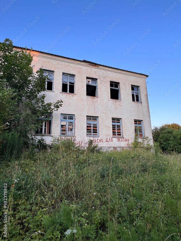 abandoned school brick building overgrown with grass and bushes with empty windows abandoned school brick building overgrown with grass and bushes with empty windows