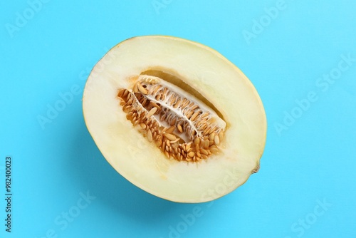 Half of fresh melon on light blue background, top view photo