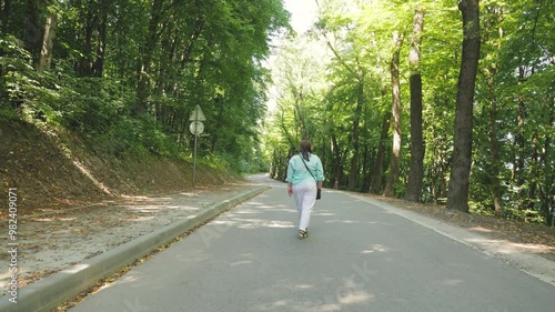 Wallpaper Mural A overweight woman in a striped shirt and white pants is walking through the forest. A woman walks alone in nature at sunset. Slow motion. Active lifestyle. Torontodigital.ca