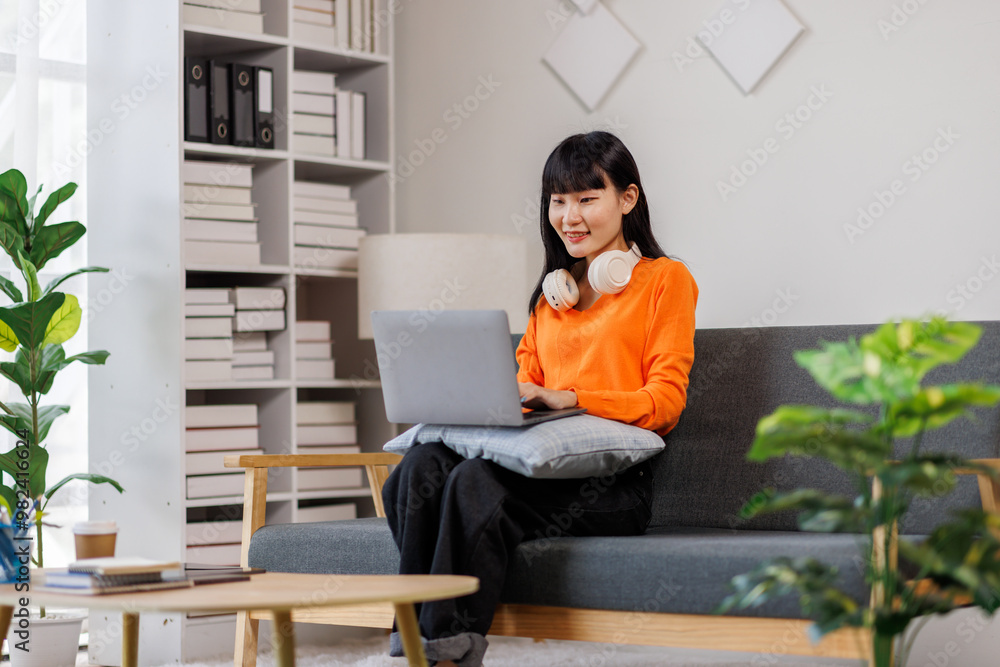A young woman of asian descent wearing headphones, deeply focused while sitting at her desk with a laptop at home.
A young woman of asian descent wearing headphones, deeply focused while sitting at her desk with a laptop at home.