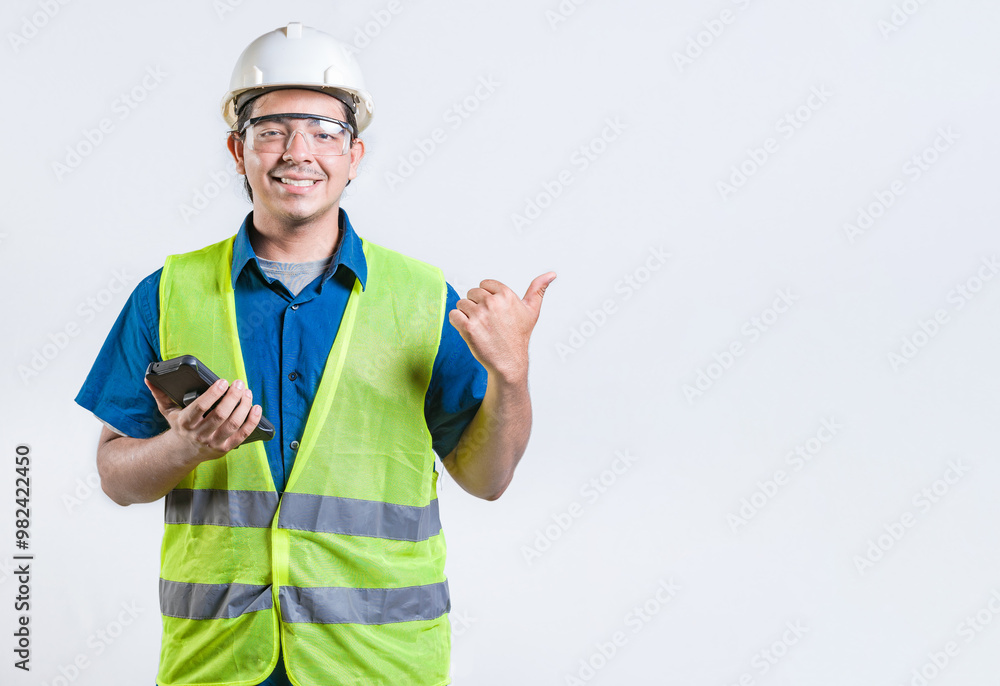 Young architect with phone pointing at blank space isolated. Smiling engineer holding phone and pointing to the side isolated Young architect with phone pointing at blank space isolated. Smiling engineer holding phone and pointing to the side isolated