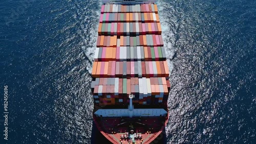 Aerial front view of a very large industrial container cargo carrier ship passing by with speed