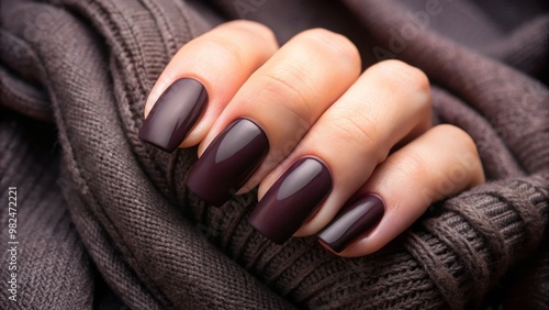 Rich, dark matte polish glimmers under the light on a woman's perfectly manicured hand, a fusion of elegance