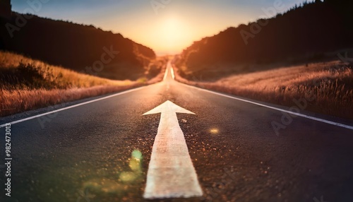 White arrow sign on the asphalt road with rising sun on background. Business concept picture of success photo