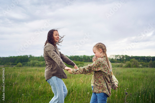 a mother and two sisters circle in the field holding hands photo