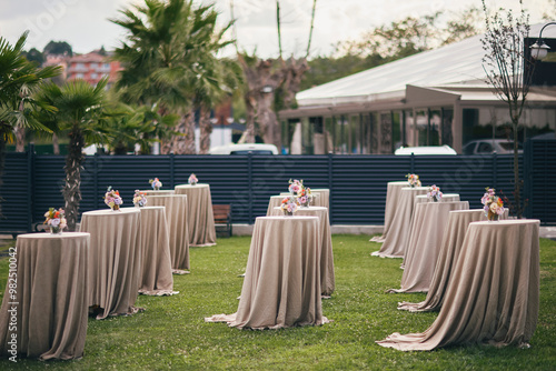 Obraz na płótnie A stylish outdoor event space with round tables, lush greenery, and colorful floral arrangements w salonie