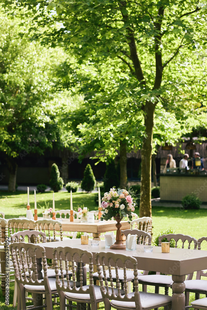 Charming Outdoor Garden Event with Wooden Tables, Soft Floral Decor, and Natural Greenery Ambience
