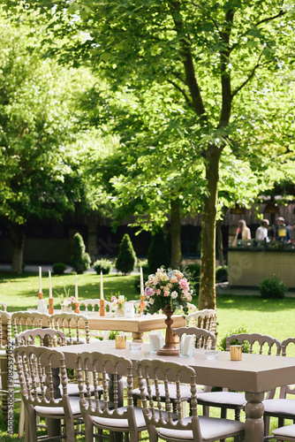 Obraz na płótnie Charming Outdoor Garden Event with Wooden Tables, Soft Floral Decor, and Natural Greenery Ambience w salonie
