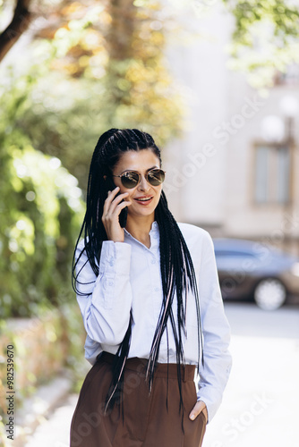 Business woman with braided hair talking on the phone outside the street