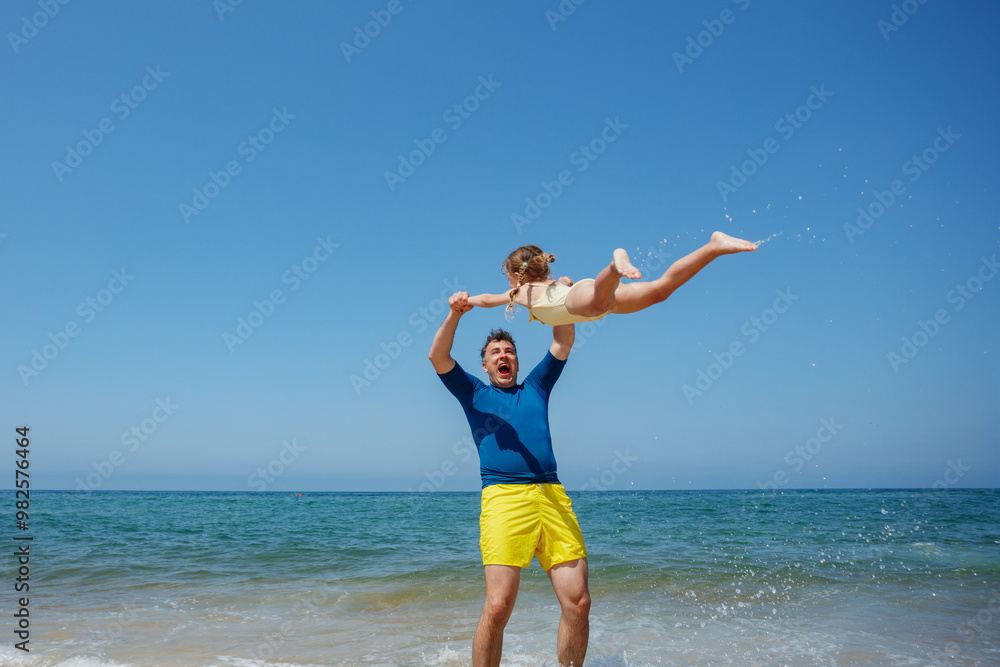Beach fun: dad swings his daughter over the waves, play a plane Beach fun: dad swings his daughter over the waves, play a plane