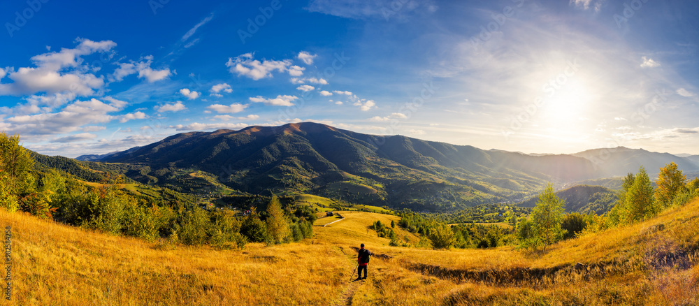 panorama of rural landscape in carpathian mountains in autumn. sunny day. grassy field and rolling hills. countryside scenery of ukraine. village in the distant valley