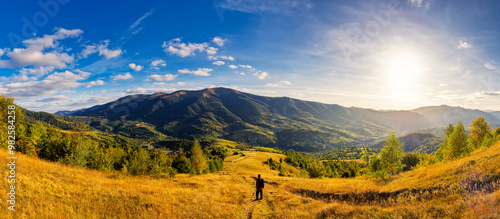 Obraz na płótnie panorama of rural landscape in carpathian mountains in autumn. sunny day. grassy field and rolling hills. countryside scenery of ukraine. village in the distant valley w salonie