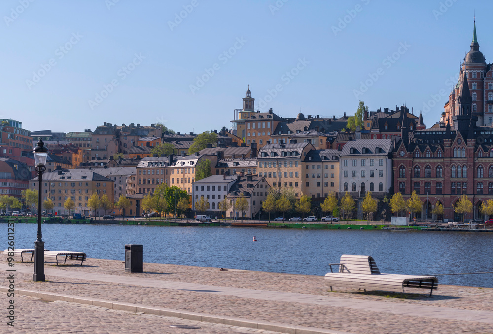 Fototapeta premium The block Mariaberget in the district Södermalm a pier with bench at the bay Riddarfjärden, a sunny summer day in Stockholm