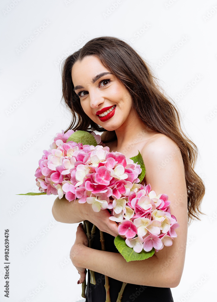 Young woman with pink flowers on white backdrop. A smiling young woman holds vibrant pink flowers, showcasing her joyful expression in a minimalist setting with a white backdrop. Young woman with pink flowers on white backdrop. A smiling young woman holds vibrant pink flowers, showcasing her joyful expression in a minimalist setting with a white backdrop.
