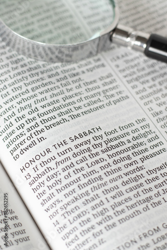 Honor the Sabbath verse in open holy bible book with magnifying glass. Christian biblical concept of seventh day rest, blessing, and obedience to God Jesus Christ.