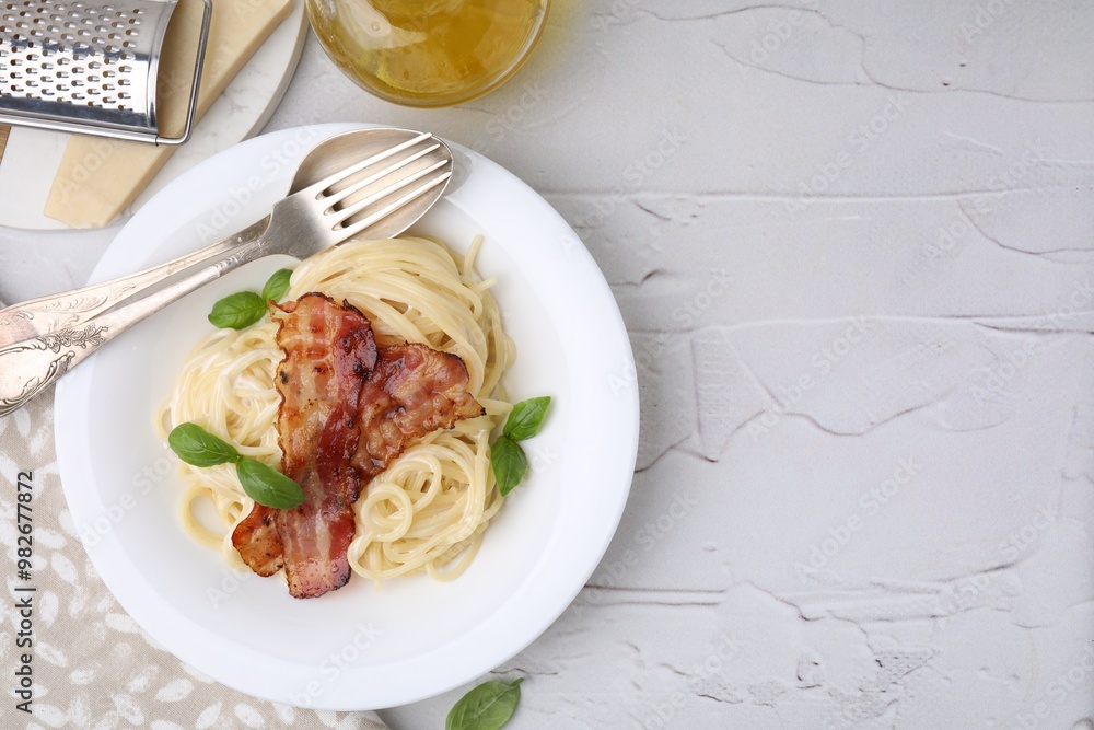 Delicious pasta Carbonara, cheese, oil, cutlery and grater on light textured table, flat lay. Space for text Delicious pasta Carbonara, cheese, oil, cutlery and grater on light textured table, flat lay. Space for text
