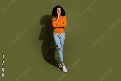 Full length photo of shiny attractive lady dressed orage pullover arms crossed looking empty space isolated green color background