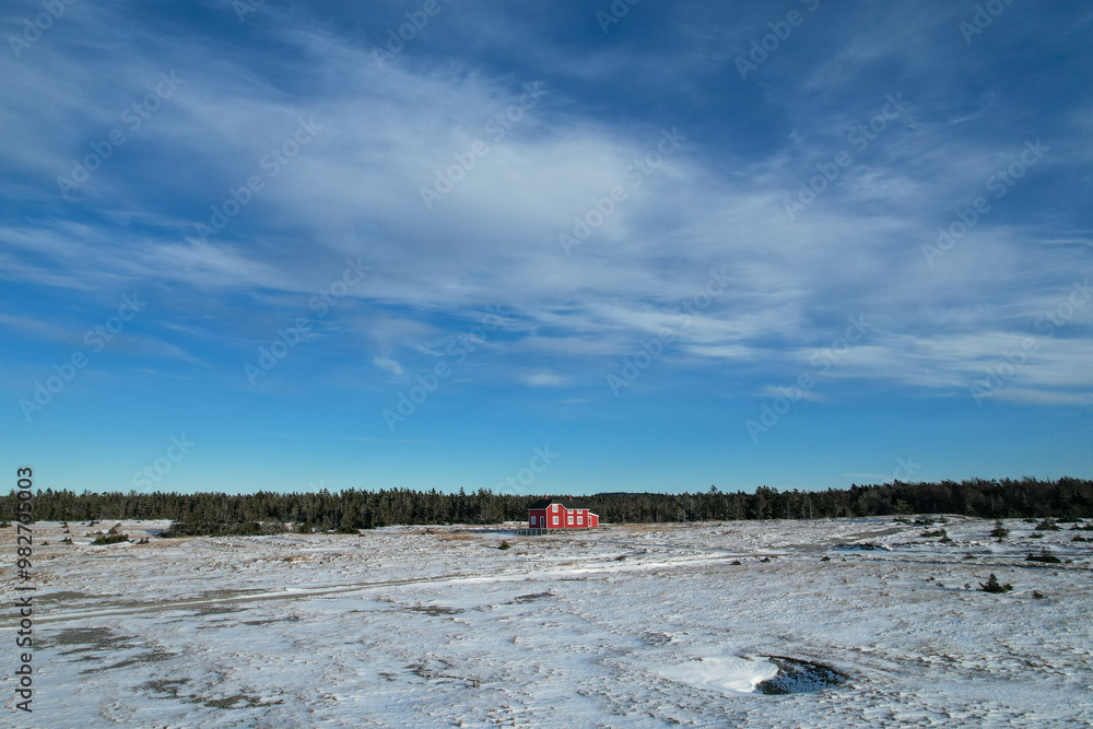 Ancient Refurbished Large Red Canadian House in Sainte-Claire Bay, in the Middle of a Frozen Snow Meadow during Winter. The old village from the 18th century is visible from above.