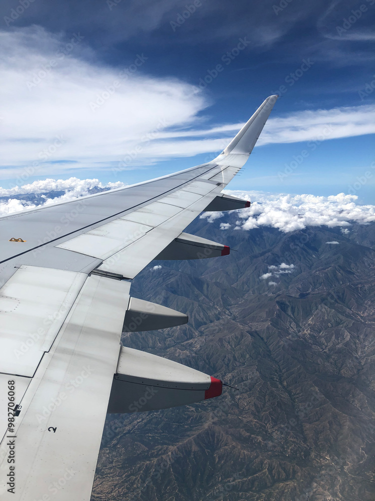 Fototapeta premium A view from an airplane window of beautiful mountains with little snow and clouds