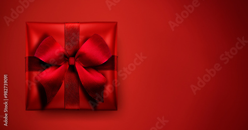 Rotes Geschenk mit Schleife vor Rotem Hintergrund