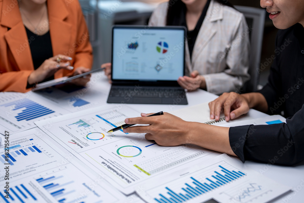 Business team analyzing financial charts on desk during meeting Business team analyzing financial charts on desk during meeting