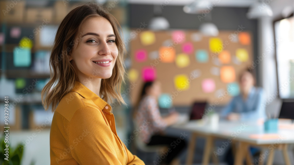 A confident woman smiles while standing in a creative office environment, symbolizing success and positivity in a professional setting. A confident woman smiles while standing in a creative office environment, symbolizing success and positivity in a professional setting.