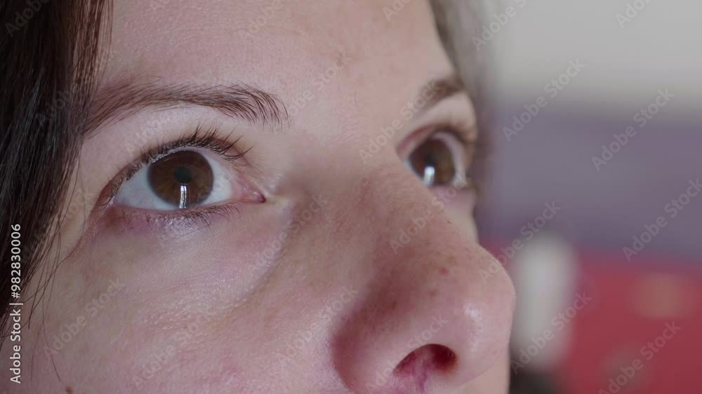 A close-up vertical shot focusing on the eyes of a young dark-haired woman looking upwards. The scene captures her thoughtful gaze and emotion. A close-up vertical shot focusing on the eyes of a young dark-haired woman looking upwards. The scene captures her thoughtful gaze and emotion.