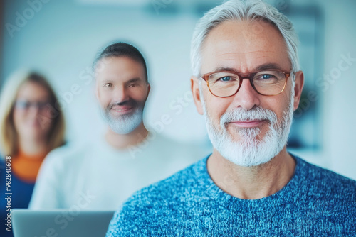 Smiling senior man with a white beard and glasses in a professional setting.