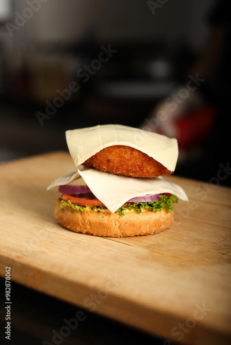 Stop motion of assembling burger. burber bon a chopping wood with Lettuce, tomatoes, onion, cheese and  veg patty. burger garnished with small tomatoes and veggeis  photo