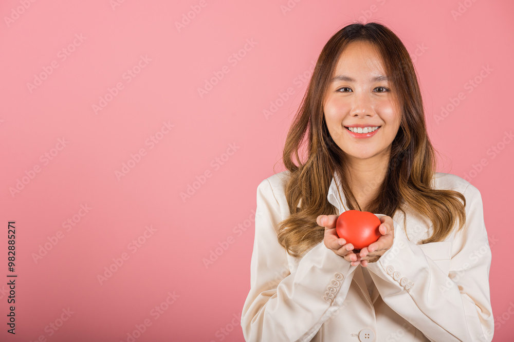 Smiling woman confidence showing holding red heart with her hand palm isolated pink background, Asian happy portrait beautiful young female send love and happy valentine in studio shot, copy space Smiling woman confidence showing holding red heart with her hand palm isolated pink background, Asian happy portrait beautiful young female send love and happy valentine in studio shot, copy space