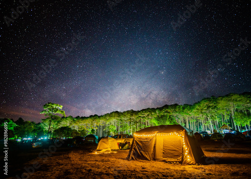 A tent is illuminated by string lights under a starry night sky at Phu Hin Rong Kla National Park, Thailand.