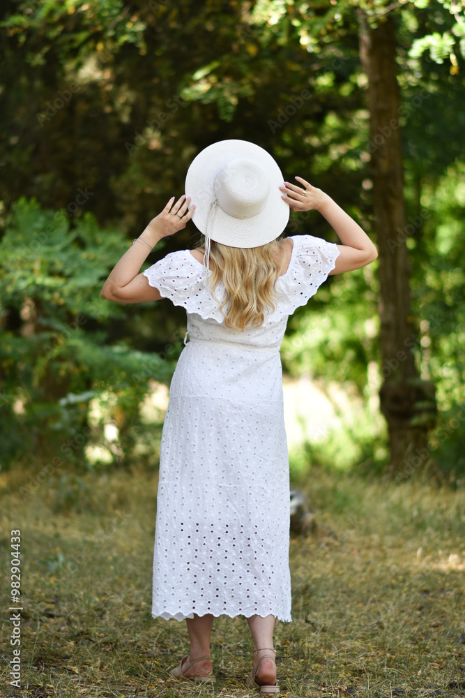 Fototapeta premium Closeup back view of woman in white hat looking out towards .