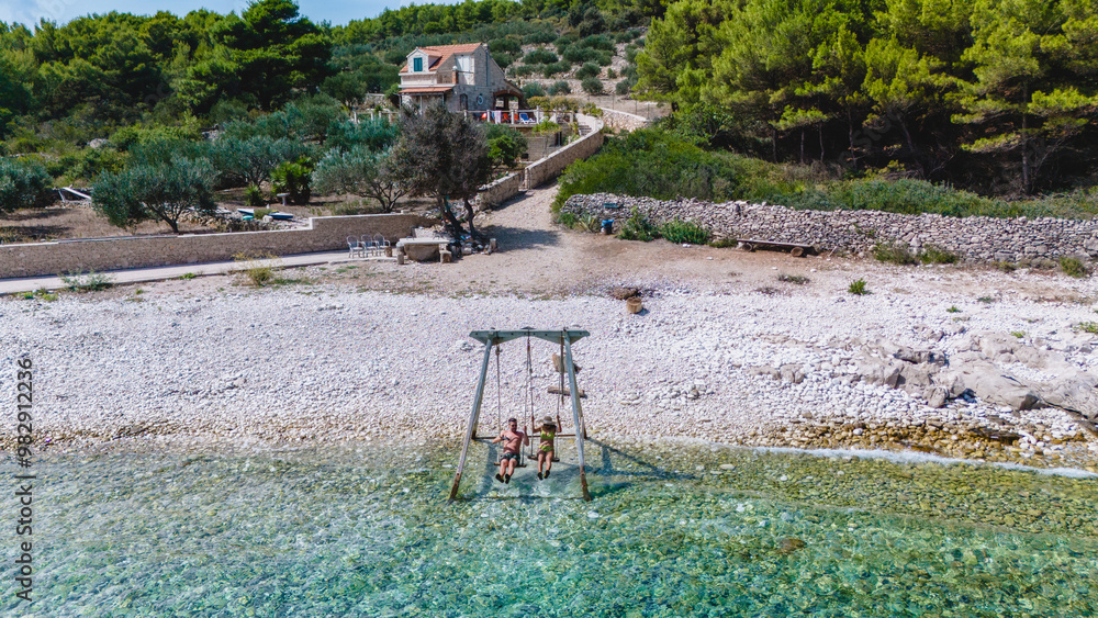 Two friends enjoy a carefree swing over crystal-clear waters on Brac Island, surrounded by lush greenery and charming hills. The vibrant atmosphere captures the essence of summer leisure. Two friends enjoy a carefree swing over crystal-clear waters on Brac Island, surrounded by lush greenery and charming hills. The vibrant atmosphere captures the essence of summer leisure.