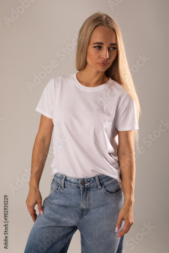 Blonde girl in white t-shirt and jeans posing on white background