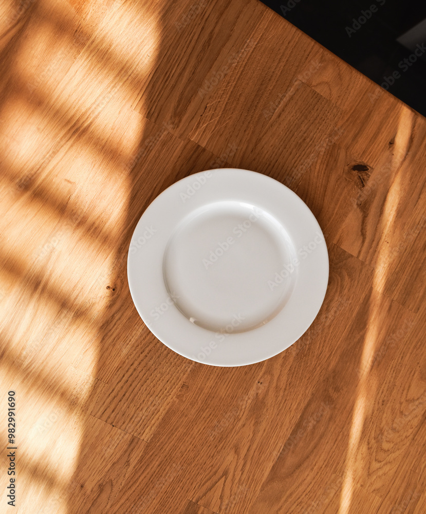 Ceramic white flat plate for food on wooden table top view Ceramic white flat plate for food on wooden table top view