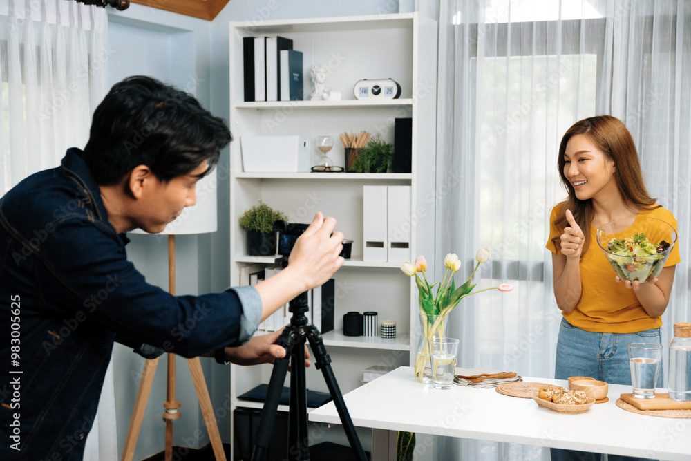 Asian beautiful woman food specialist presenting healthy meal wholegrain bun bread basket on live channel recorded video camera by smart cameraman streaming lifestyle social media online. Infobahn. Asian beautiful woman food specialist presenting healthy meal wholegrain bun bread basket on live channel recorded video camera by smart cameraman streaming lifestyle social media online. Infobahn.